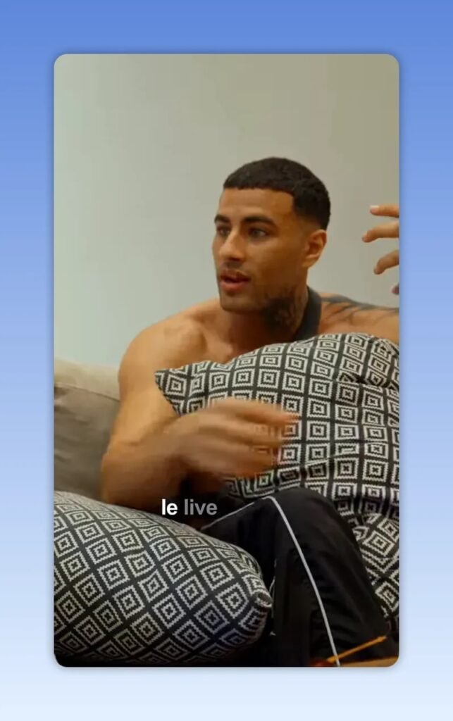 Homme assis sur un canapé tenant un coussin à motif, parlant avec un sous-titre visible