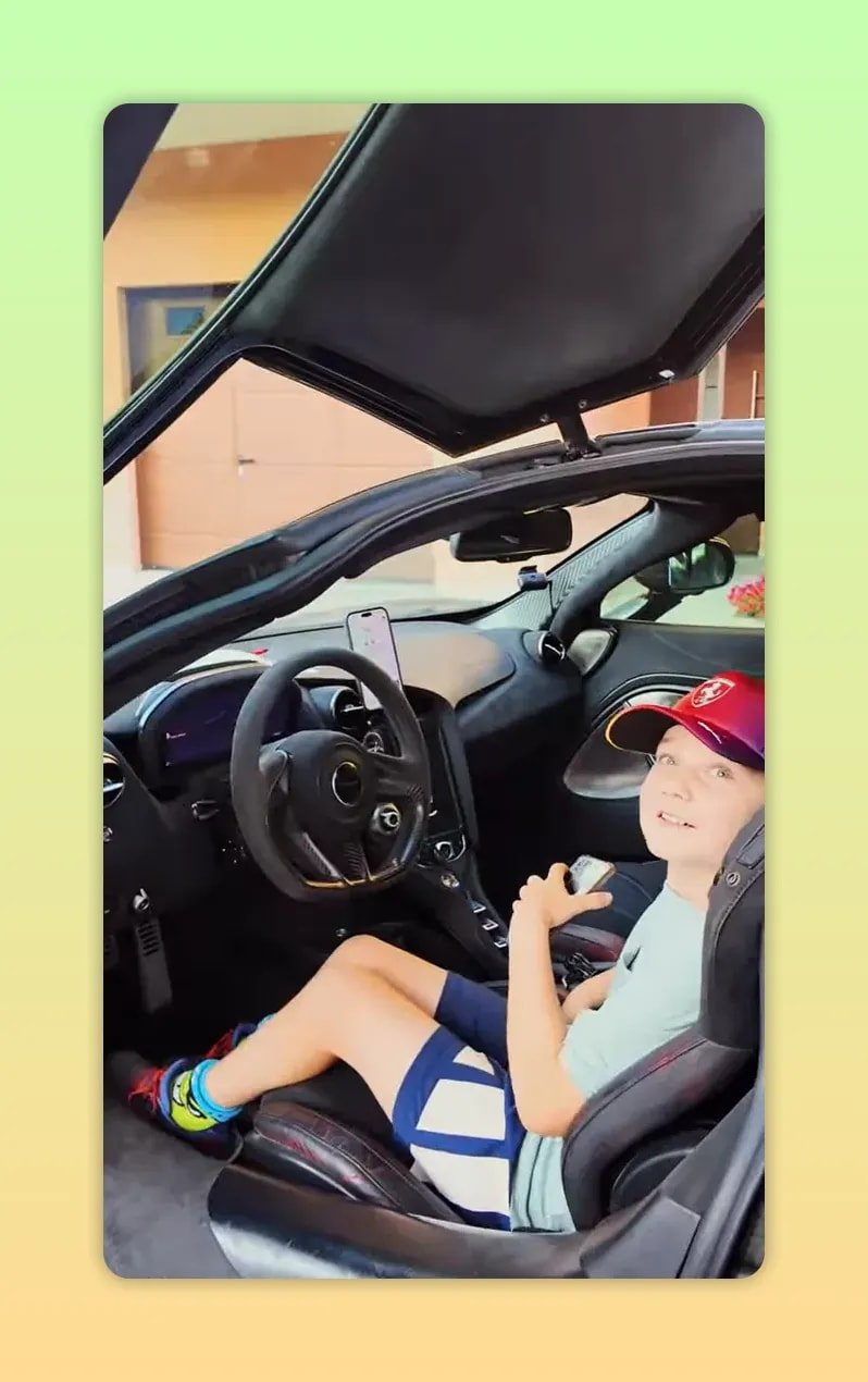 Enfant souriant assis dans la McLaren avec la porte relevée au-dessus de lui