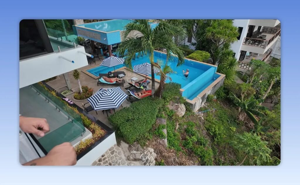 Vue plongeante sur la piscine, les terrasses et les bâtiments en contrebas depuis un balcon en hauteur